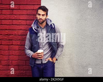 L'inverno non è completo senza caffè. Un giovane uomo alla moda in inverno indossa una bevanda calda. Foto Stock