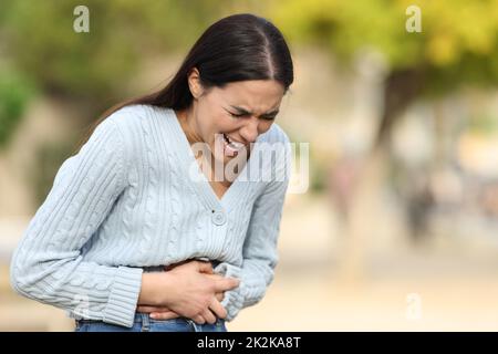 Donna che soffre mal di pancia lamentarsi per strada Foto Stock