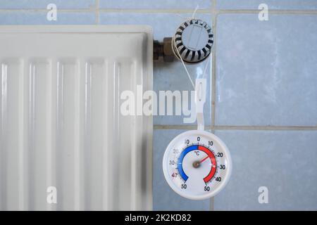 Radiatore, valvola e termometro che mostrano bassa temperatura, carenza di gas e petrolio da riscaldamento a causa dell'embargo del petrolio e del gas russi in europa Foto Stock