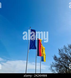 Le bandiere di Ucraina, Germania e Unione europea volano fianco a fianco contro il cielo blu. Foto Stock