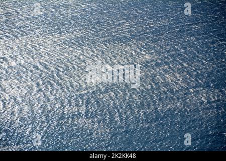 I riflessi del mare disegnano un tessuto fatto di riflessi infiniti sull'ondulazione delle onde. Foto Stock