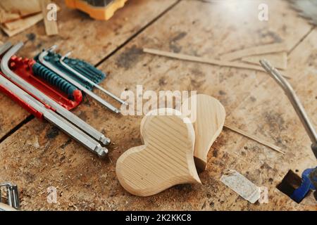 Due forme decorative di cuore in legno su un banco di lavoro di Falegnameria Foto Stock