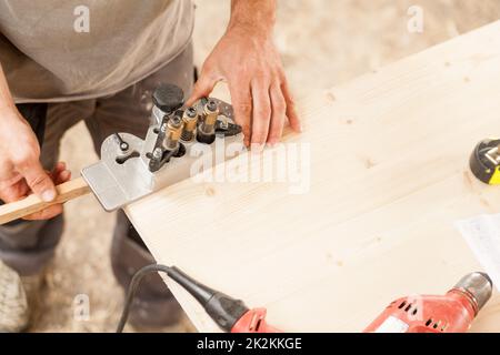 woodworker che tiene una dima su una tavola di legno Foto Stock