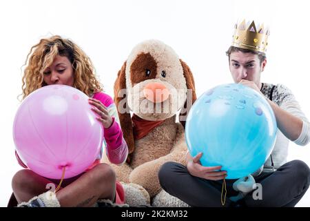 Giovane donna con uomo che soffia palloncini grande festa Foto Stock