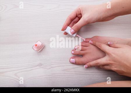 mano di una donna che applica lo smalto del chiodo rosa Foto Stock