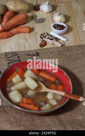 Stufato di manzo abbondante con patate e carote sulla busta di patate vintage burlap Foto Stock