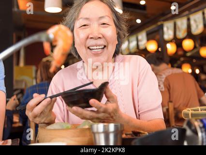 Felice madre e famiglia che cena e festeggia la giornata delle madri al ristorante Foto Stock