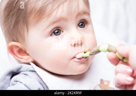 bambina nutrita dalla mano di sua madre Foto Stock