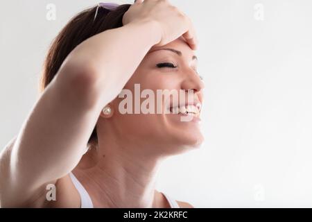 Felice giovane donna sorridente che tiene la mano alla fronte Foto Stock