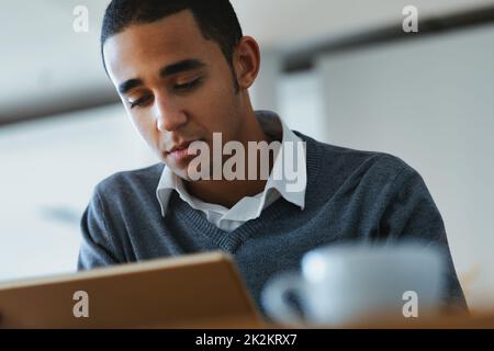 Serio giovane uomo nero ingessato nella lettura su un tablet pc Foto Stock