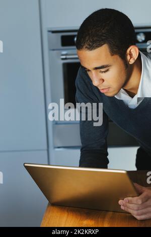 Giovane uomo d'affari che usa un computer portatile in cucina Foto Stock