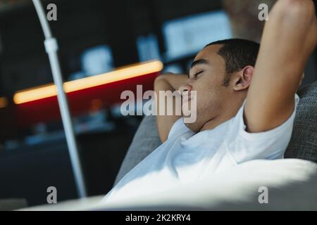 Un giovane stanco che si snooze su una comoda sedia Foto Stock