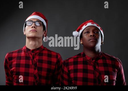 Due uomini amici che indossano cappelli di Natale e camicie a plaid Foto Stock