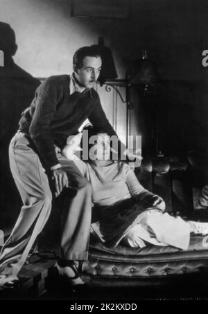 L'animatore e produttore americano Walt Disney si trova dietro la moglie Lillian Bounds, mentre si siede in un sedile d'amore, intorno al 1933 Foto Stock