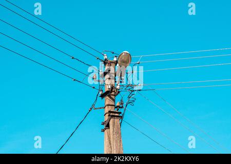 Fili elettrici appesi su un palo con una lampada di illuminazione Foto Stock