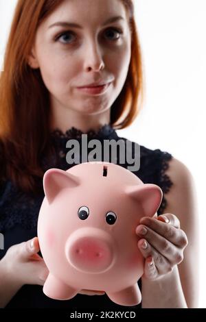 Travagliata giovane donna grave in possesso di una banca rosa piggy Foto Stock