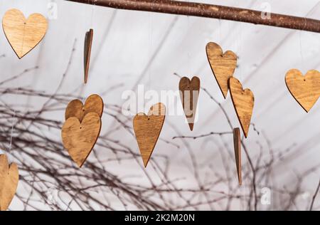 Ornamenti a forma di cuore. Ornamenti in legno sui rami. Cuori tagliati di legno. Tema autunnale. Foto Stock