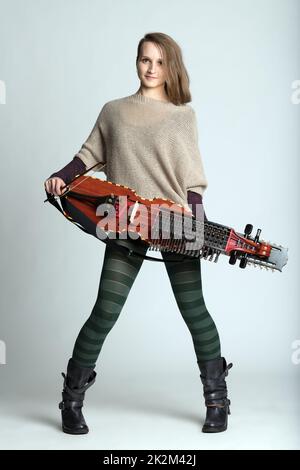 Giovane musicista alla moda che tiene un nyckelharpa Foto Stock