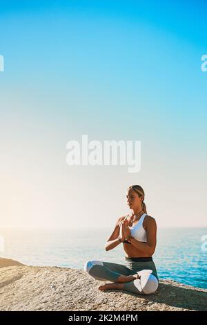 Sono tutto in me. Shot di una giovane atletica che pratica yoga sulla spiaggia. Foto Stock