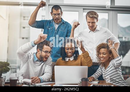 I numeri sono in e sembrano buoni. Scatto di colleghi che fanno il tifo per qualcosa sullo schermo di un notebook. Foto Stock