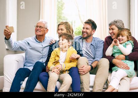 Questa è la nostra grande e bella famiglia. Scatto di una famiglia multigenerazionale seduta sul divano a casa. Foto Stock