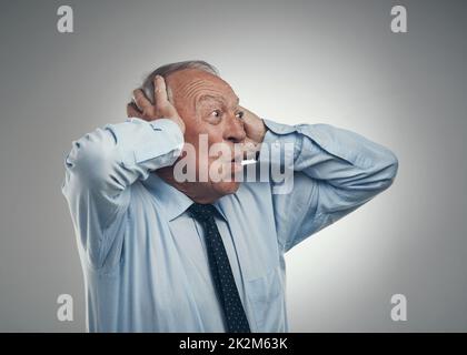 Whoa lo ha visto. Scatto di un uomo d'affari senior in piedi su uno sfondo grigio studio con la testa nelle sue mani e guardando scioccato. Foto Stock