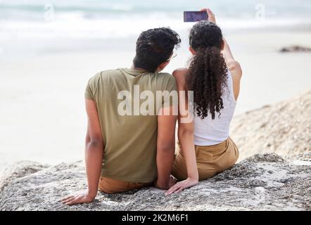 I selfie estivi sono i nostri preferiti. Scatto di una giovane coppia che prende un selfie alla spiaggia. Foto Stock