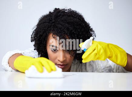 Durante la pulizia, essere scrupolosi. Colpo di una giovane donna spruzzando giù un contatore per pulirlo. Foto Stock