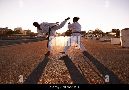 Rivolto verso l'alto...due sportivi che si affacciano verso l'alto e praticano il karate indossando il gi. Foto Stock