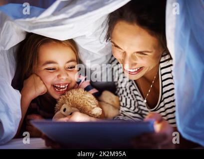 Ama le sue storie. Scatto corto di una giovane donna incinta attraente che legge sua figlia una storia di doratura su un tablet. Foto Stock