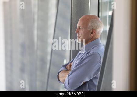 Uomo anziano dai capelli grigi in piedi nel profondo del pensiero Foto Stock