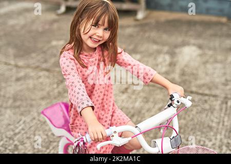 Lasciate che esplorino il mondo. Ritratto di una bambina adorabile che guida la sua bici all'aperto. Foto Stock