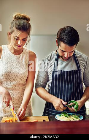 Il cibo ha un sapore migliore quando cuciniamo insieme. Shot di una giovane coppia che prepara il cibo insieme a casa. Foto Stock