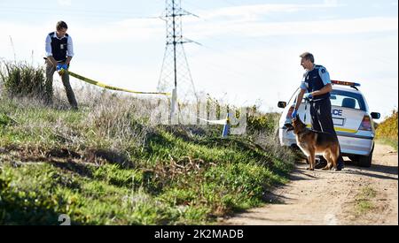 Lasciate che gli ottenga il profumo. Sparato di due poliziotti che hanno indonato una scena criminale con nastro di polizia. Foto Stock