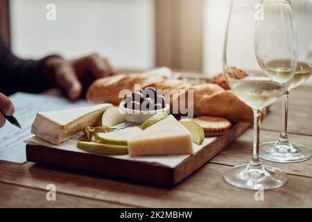 Qualcosa da andare con il vostro vino. Shot di un uomo gustando un piatto di formaggi e degustando vini diversi. Foto Stock