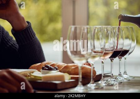 Venite a gustare un vino pluripremiato. Shot di un uomo gustando un piatto di formaggi e degustando vini diversi. Foto Stock