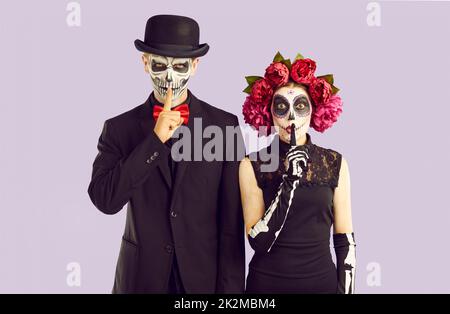 Coppia in costumi di Halloween mettere le dita alle labbra chiedendo di essere in silenzio e mantenere segreto Foto Stock