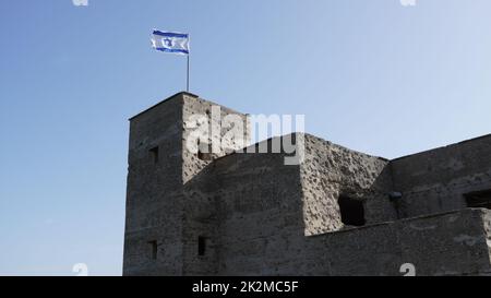 Le rovine della British mandate Police Station a Ein Tina all'inizio della riserva naturale del torrente Amud, alta Galilea, Israele settentrionale. Edificio storico in cemento con la bandiera israeliana in cima Foto Stock