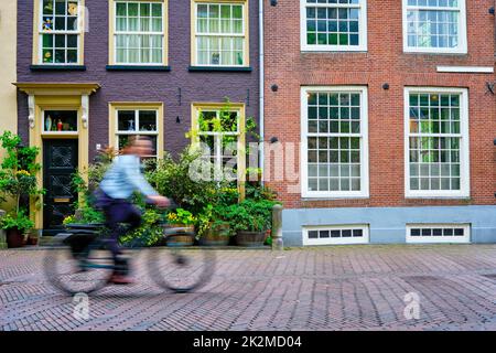 Ciclista ciclista uomo in bicicletta molto popolare mezzi di trasporto in Olanda in via di Delft, Paesi Bassi Foto Stock