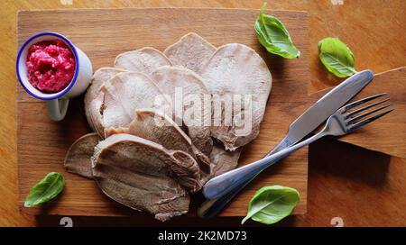 Lingua di manzo servita salsa di rafano e basilico sul tagliere. Carne succosa e tenera un ottimo antipasto. Vista dall'alto Foto Stock