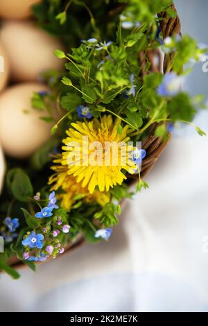 Bel bouquet primaverile in un cesto di legno con uova dipinte di Pasqua, uova con facce carine. Cartolina di Pasqua. Primo piano. Foto Stock