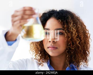 Ricerca di una soluzione. Scatto corto di una giovane scienziata femminile che conduce un esperimento in laboratorio. Foto Stock