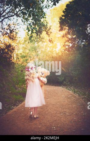 Mi chiedo dove questo porti. Girato di una bambina irriconoscibile che cammina con il suo orsacchiotto nel mezzo di una strada sterrata. Foto Stock