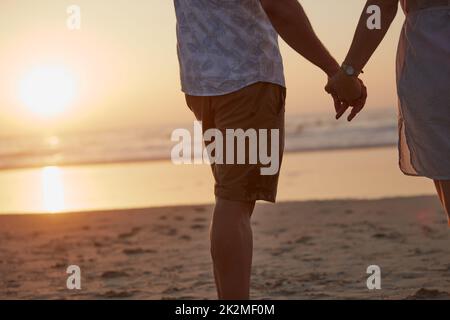 Tu la mano appartiene alla mia. Scatto retroguarato di una coppia matura che trascorre un po' di tempo in spiaggia. Foto Stock