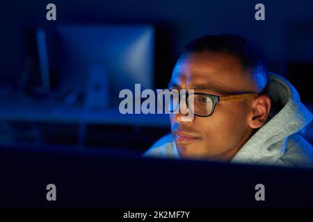 Un'occhiata più da vicino alle cose. Scatto di un giovane hacker maschio che cracking un codice computer nel buio. Foto Stock
