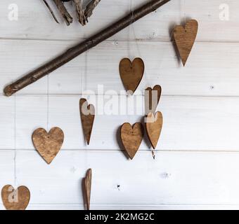 Ornamenti a forma di cuore. Ornamenti in legno sui rami. Cuori tagliati di legno. Tema autunnale. Foto Stock