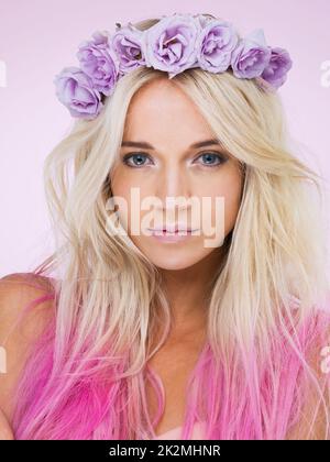 La regina di rosa e viola. Studio shot di una bella giovane donna che indossa una corona di fiori. Foto Stock