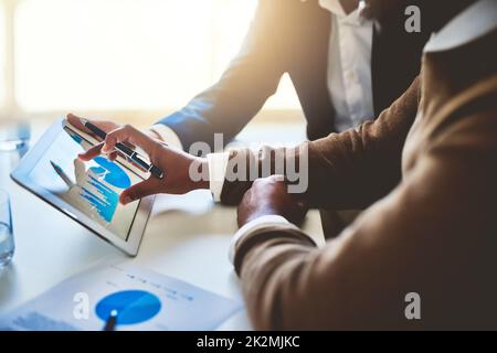 Analisi delle statistiche. Primo piano di due imprenditori non identificabili che lavorano insieme su un tablet digitale in un ufficio. Foto Stock