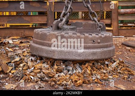 Attrezzi del commercio del junkyard. Un magnete grande che raccoglie i rifiuti in un trashyard. Foto Stock