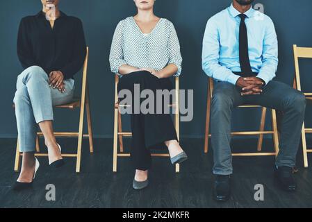 Tutto sul modo in cui ti porti. Ritagliato di un gruppo di uomini d'affari ben vestiti seduti in fila in attesa di essere intervista. Foto Stock